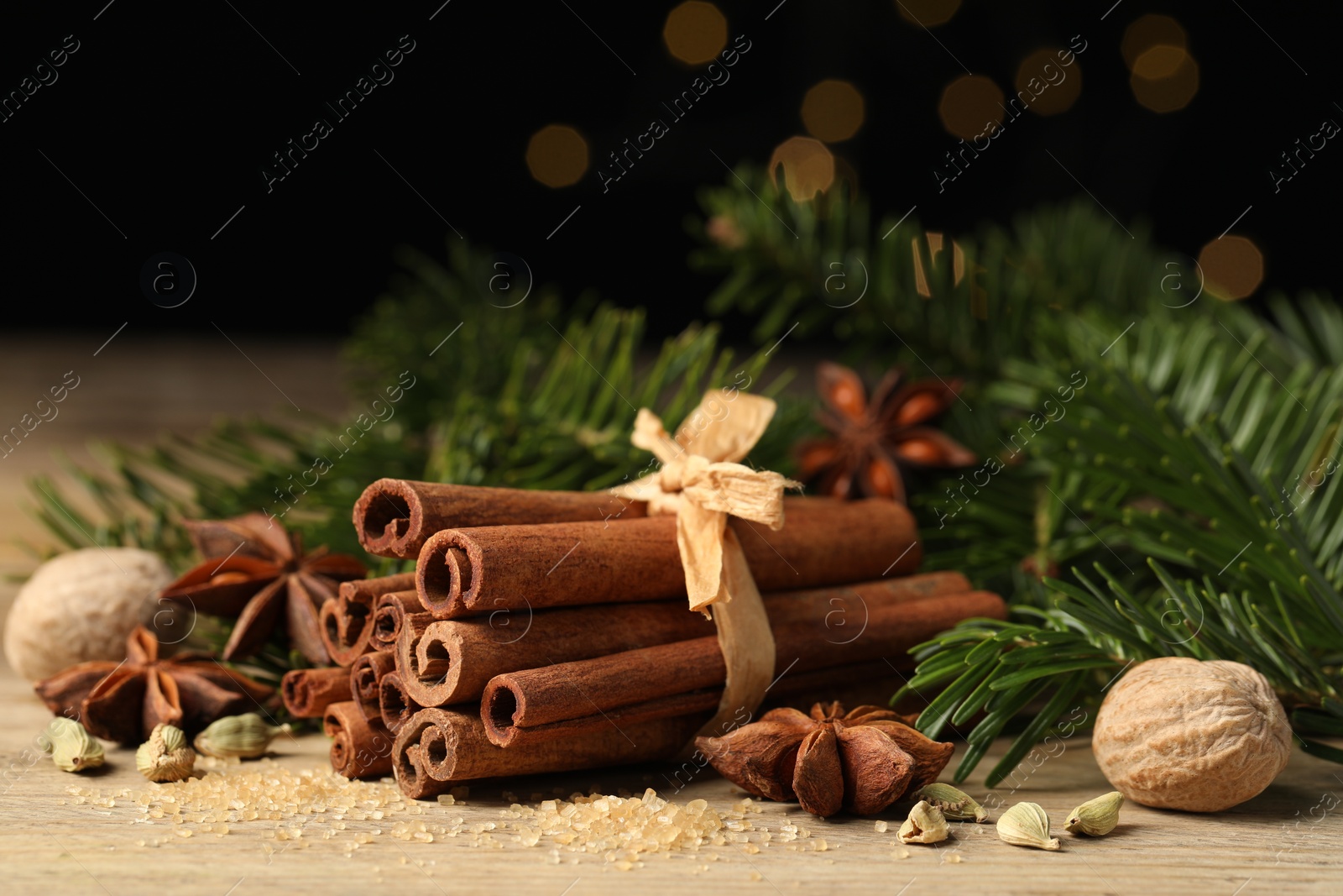 Photo of Different aromatic spices and fir branches on wooden table, closeup