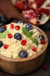 Bowl of tasty couscous with blueberries, pomegranate and mint on table, closeup