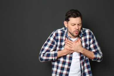 Photo of Mature man suffering from cough on dark background. Space for text