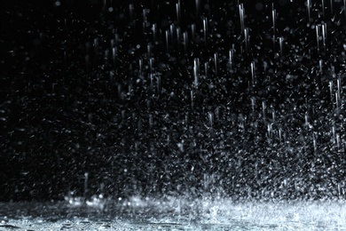 Photo of Heavy rain falling down on ground against dark background