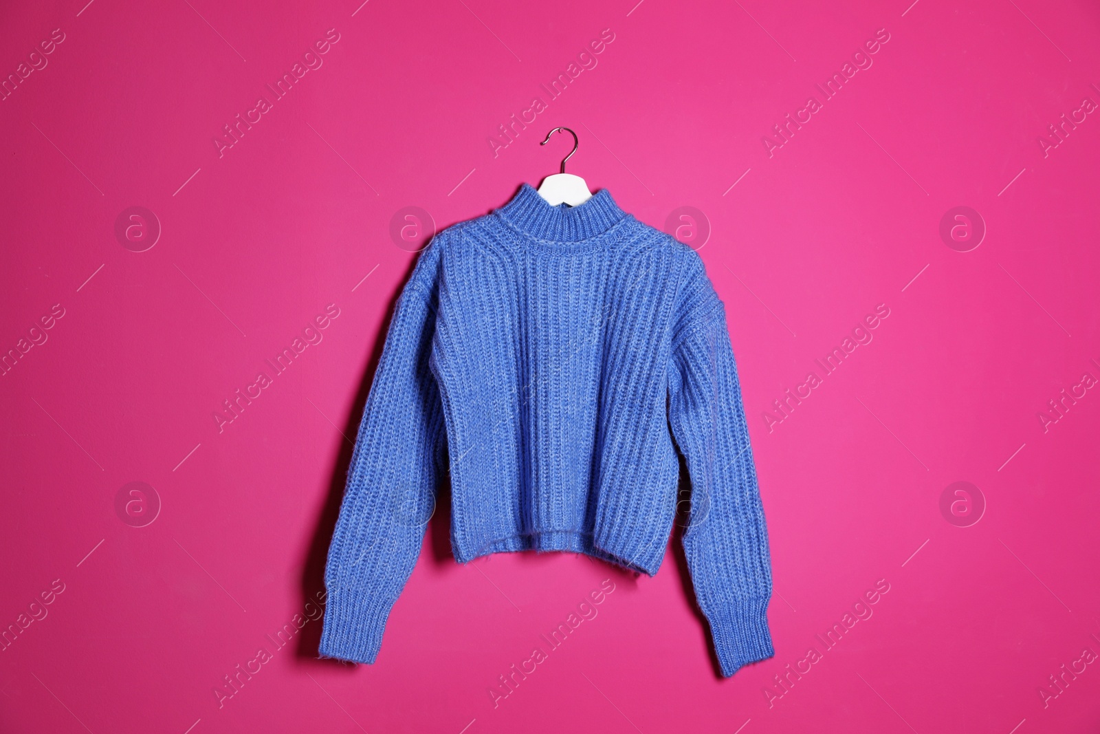 Photo of Hanger with stylish sweater on color background