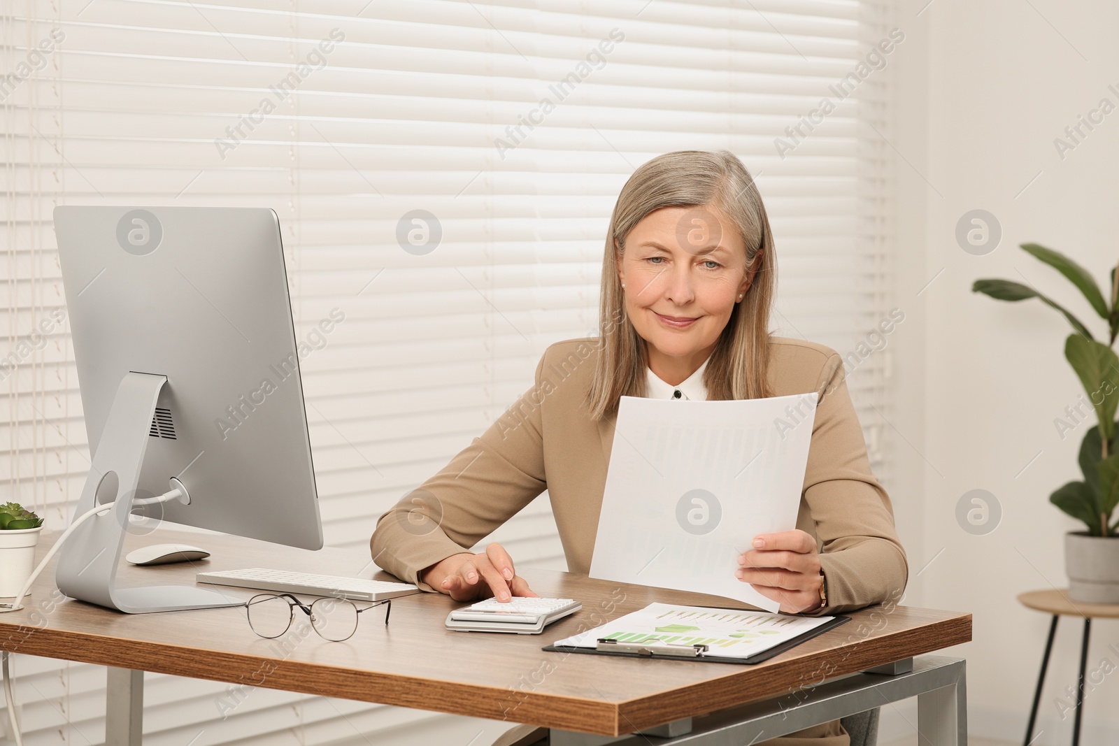 Photo of Senior accountant working at wooden desk in office