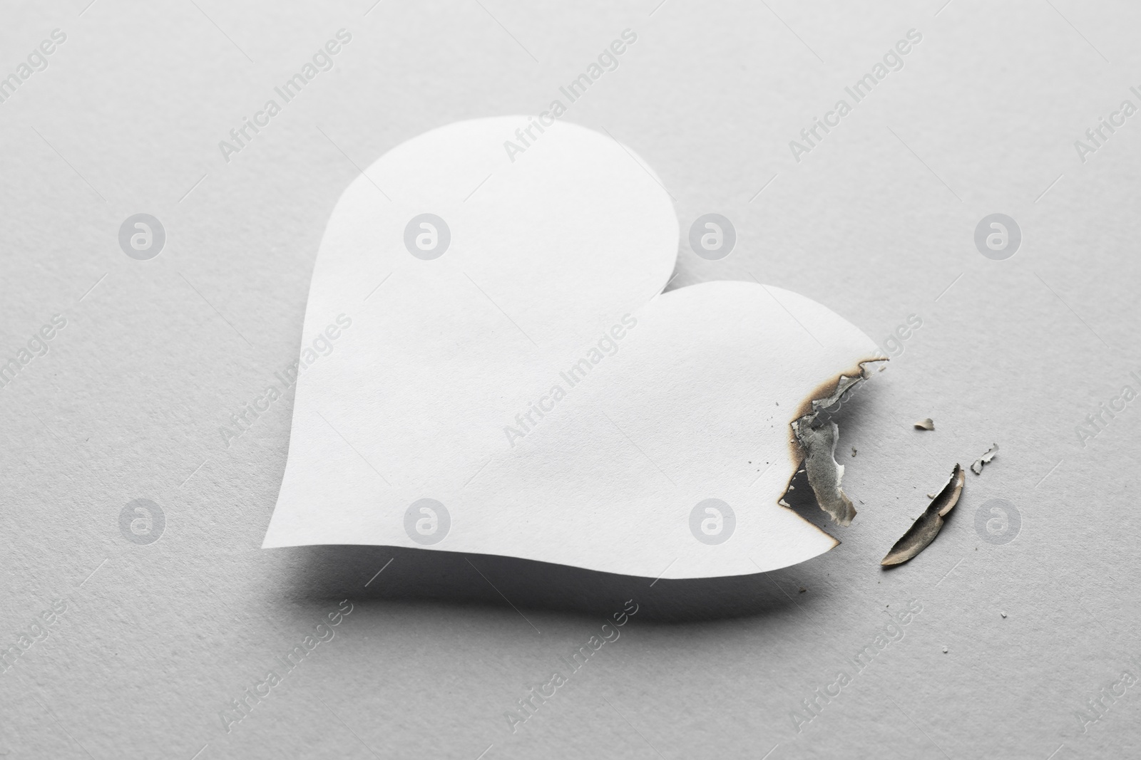 Photo of Burned paper heart on white background. Broken heart