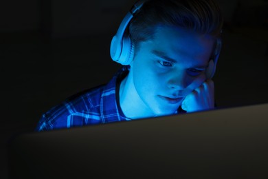 Teenage boy in headphones using computer at night. Internet addiction