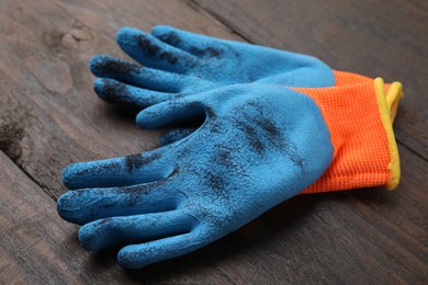 Photo of Pair of color gardening gloves on wooden table, closeup