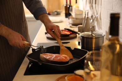 Photo of Man cooking fresh salmon steak in frying pan, closeup