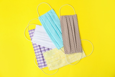 Photo of Homemade protective face masks on yellow background, flat lay