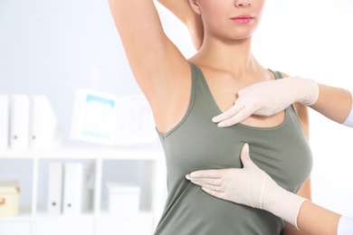 Photo of Doctor checking woman's breast at hospital, closeup. Space for text