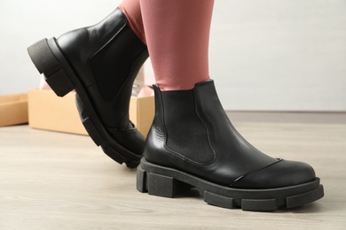 Photo of Woman wearing stylish leather boots indoors, closeup