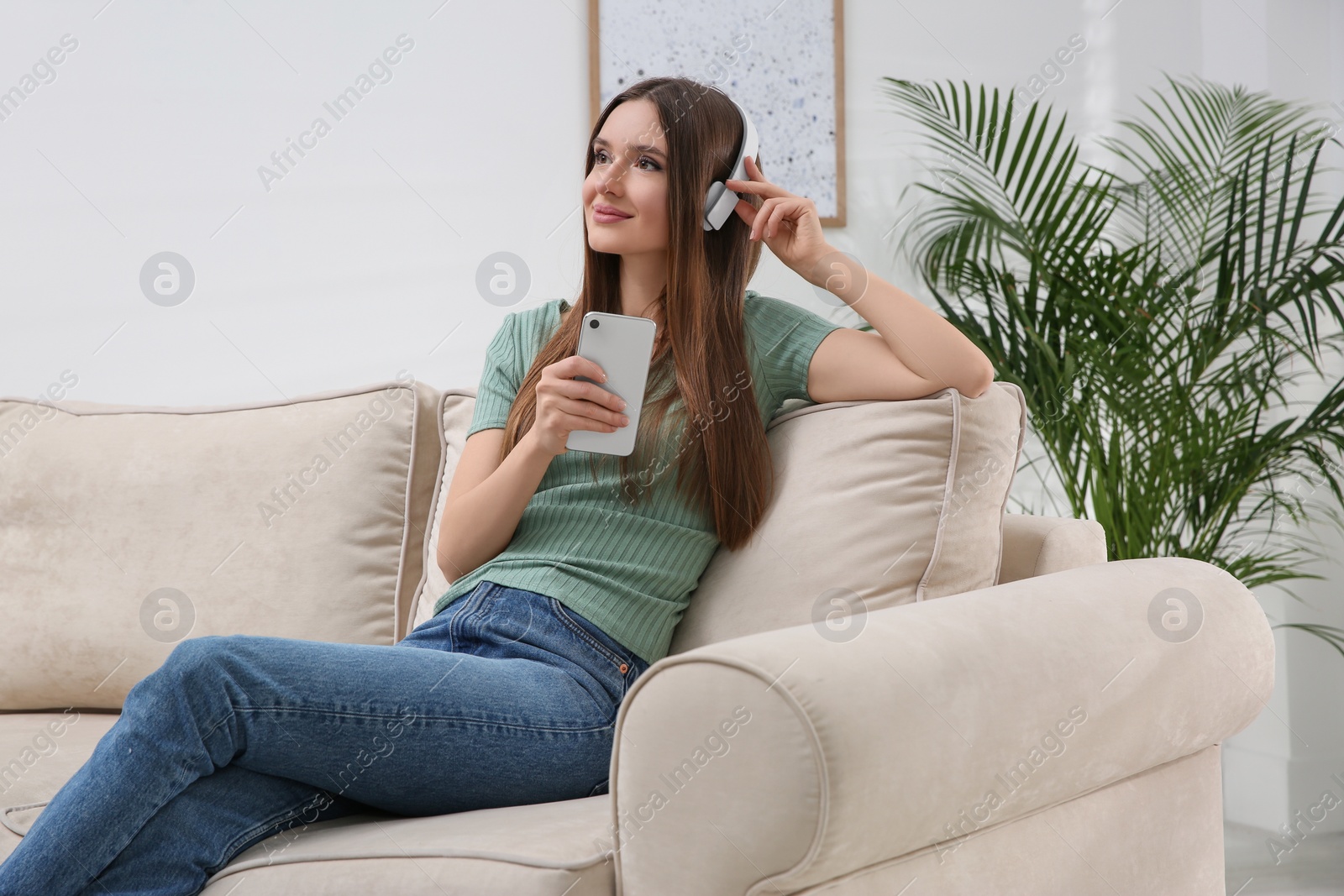 Photo of Woman listening to audiobook on sofa at home