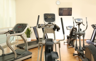Photo of Elliptical trainers and treadmills in gym. Modern sport equipment