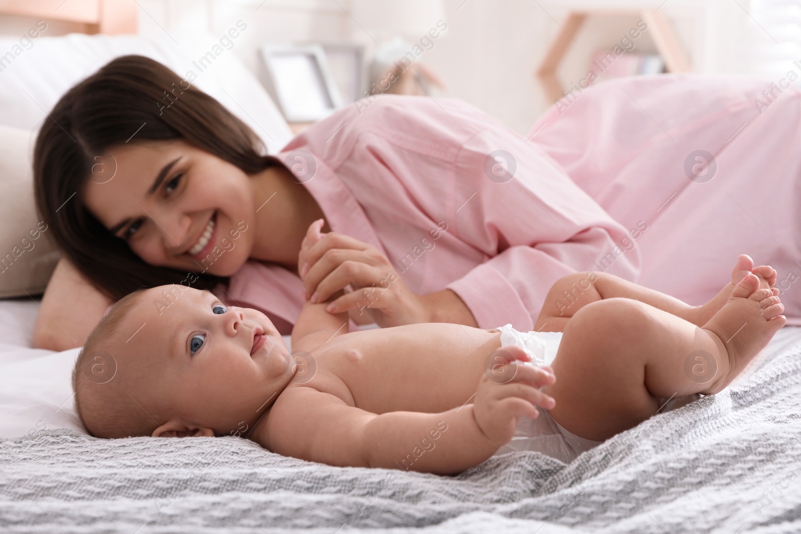 Photo of Mother with her cute baby on bed at home