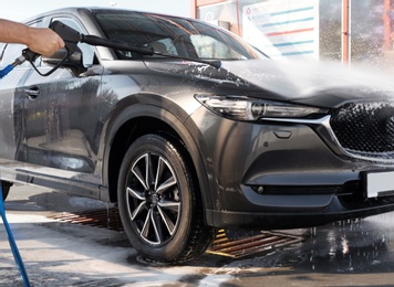 Photo of Worker cleaning automobile with high pressure water jet at car wash