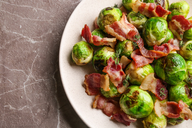 Delicious Brussels sprouts with bacon on marble table, top view