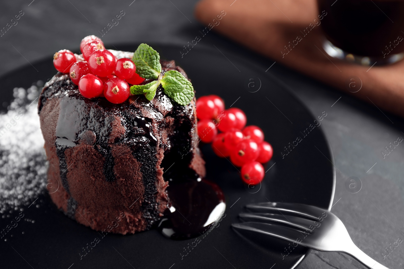 Photo of Delicious warm chocolate lava cake with mint and berries on table, closeup