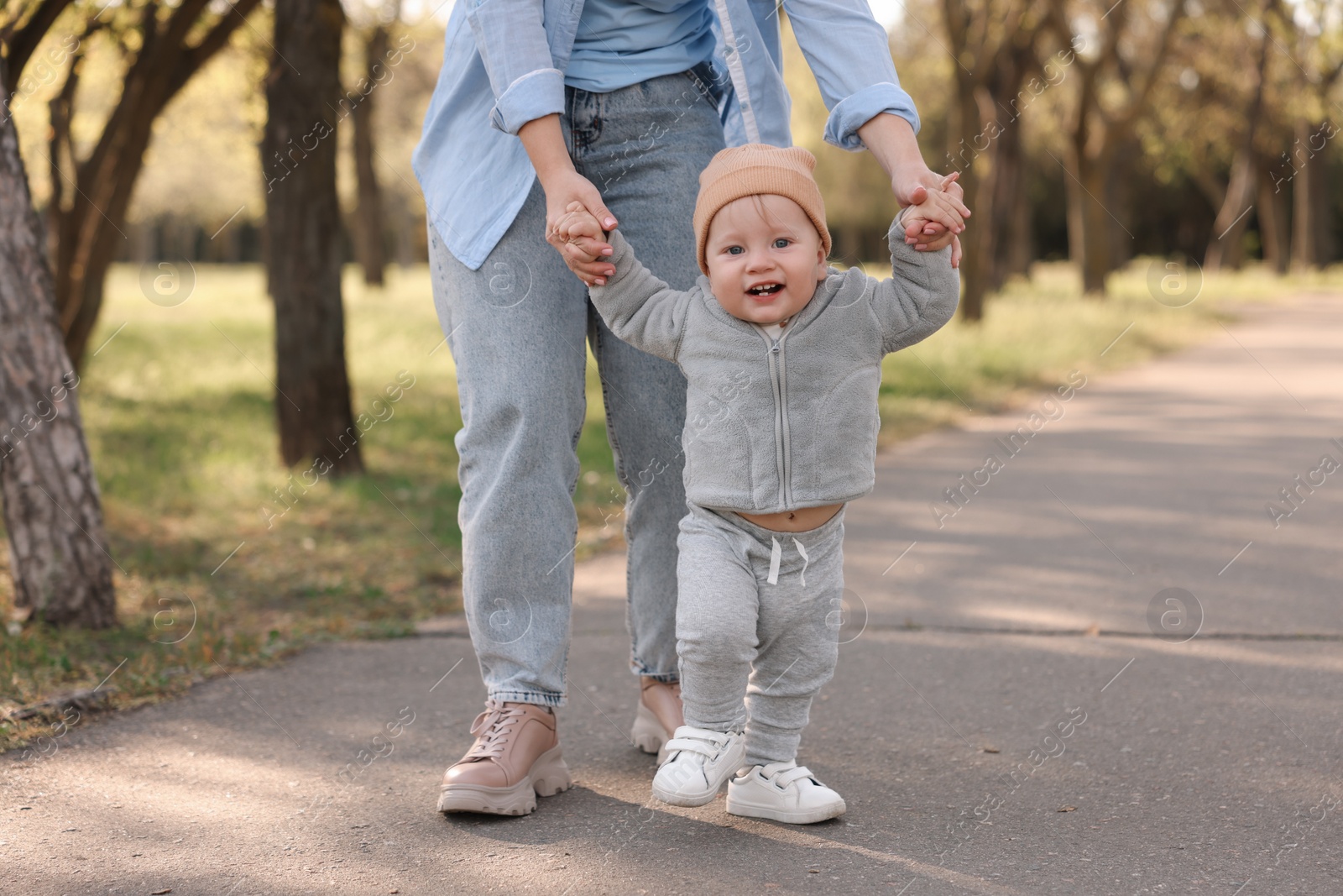 Photo of Mother teaching her baby how to walk outdoors, closeup