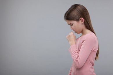 Photo of Sick girl coughing on gray background, space for text