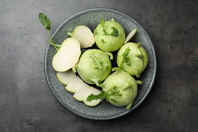 Photo of Whole and cut kohlrabi plants on grey table, top view