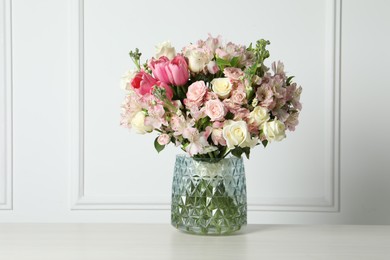 Beautiful bouquet of fresh flowers in vase on table near white wall