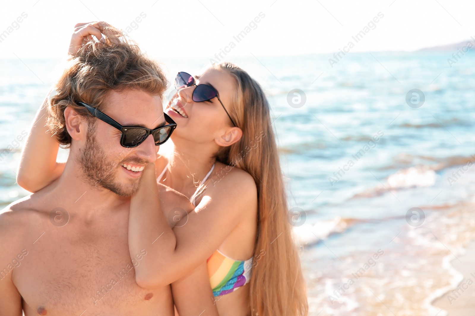 Photo of Happy young couple in beachwear spending time together on seashore. Space for text