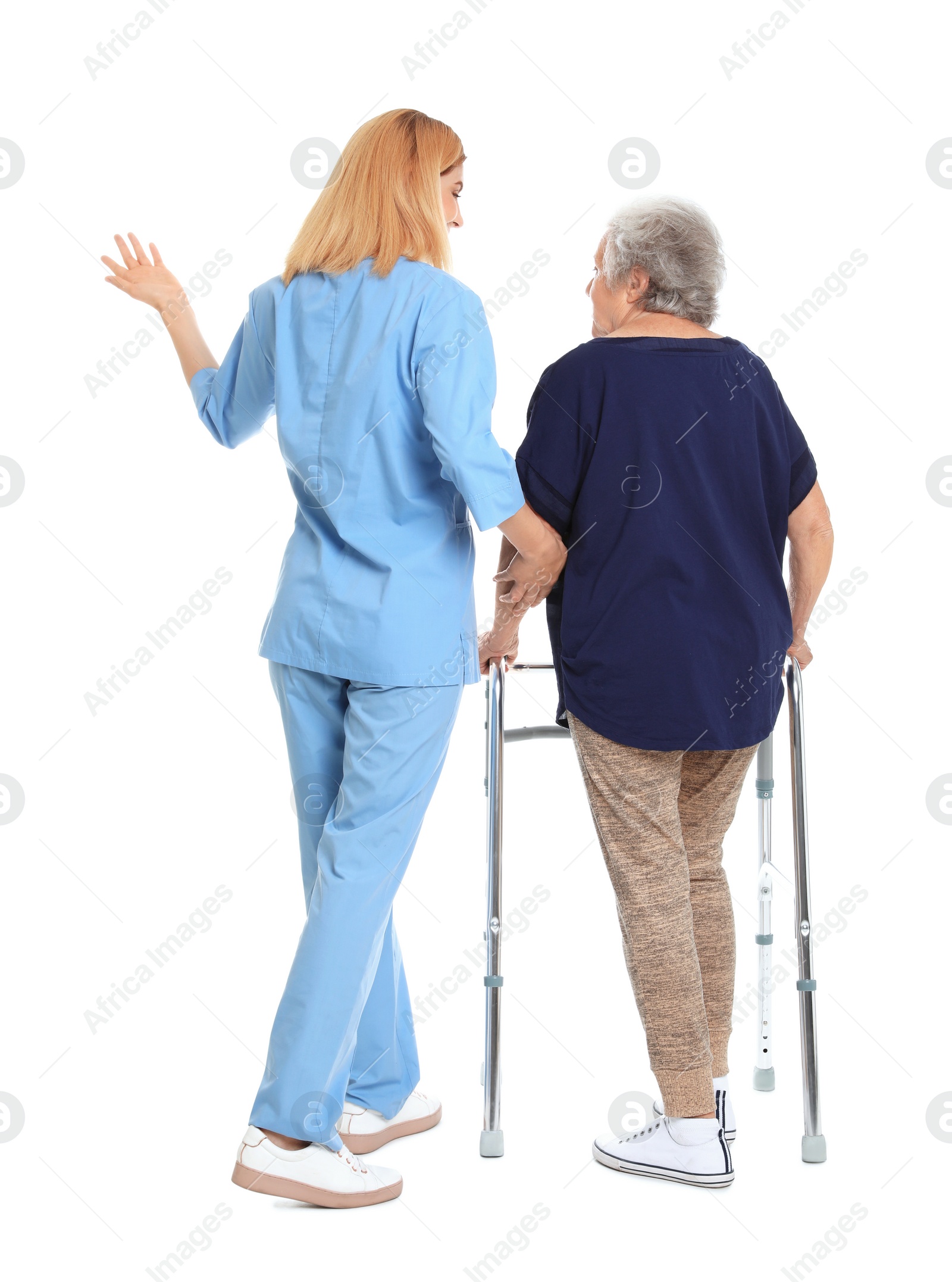 Photo of Caretaker helping elderly woman with walking frame on white background