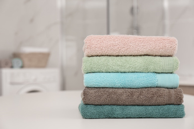Photo of Stack of color towels on white table in bathroom