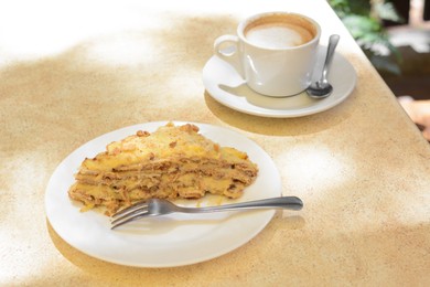 Photo of Piece of delicious cake and coffee on beige table