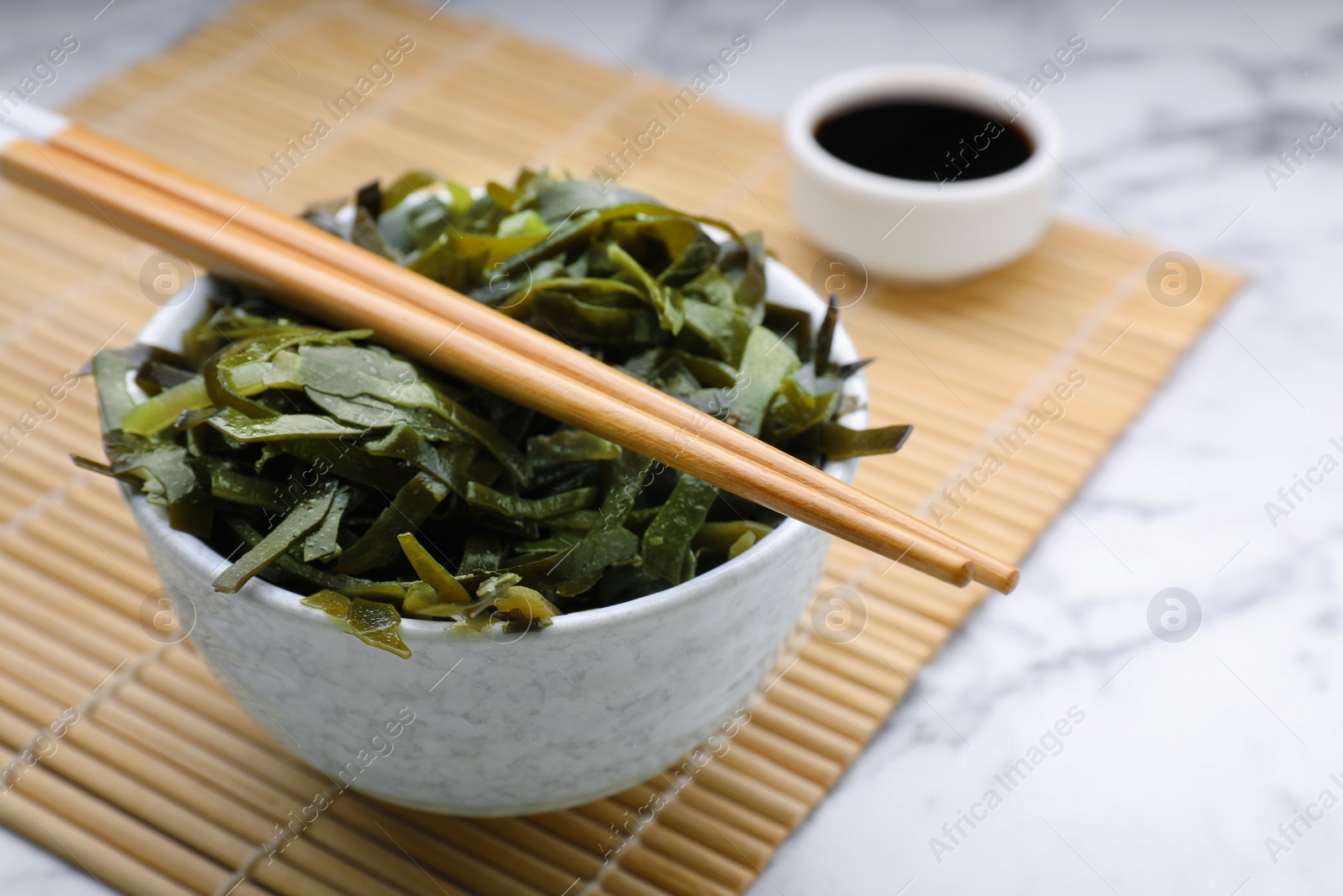 Photo of Fresh laminaria (kelp) seaweed served on white marble table