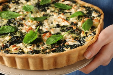 Photo of Woman holding delicious homemade spinach quiche, closeup