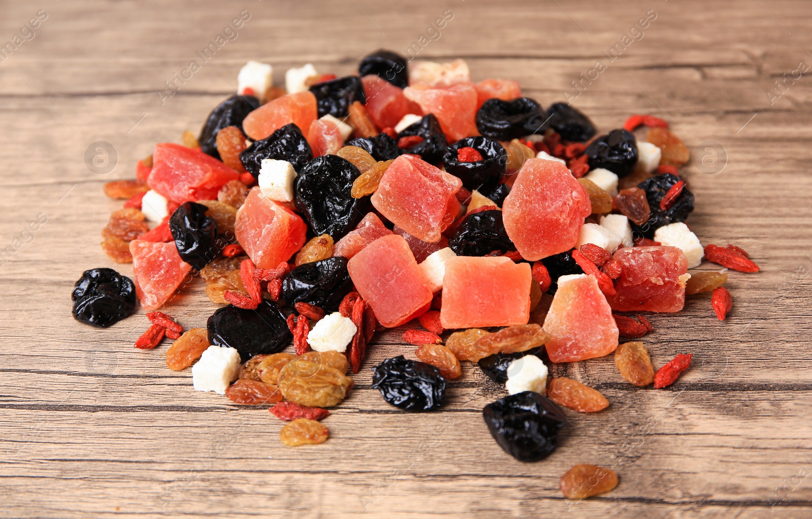 Photo of Pile of different tasty dried fruits on wooden table, closeup