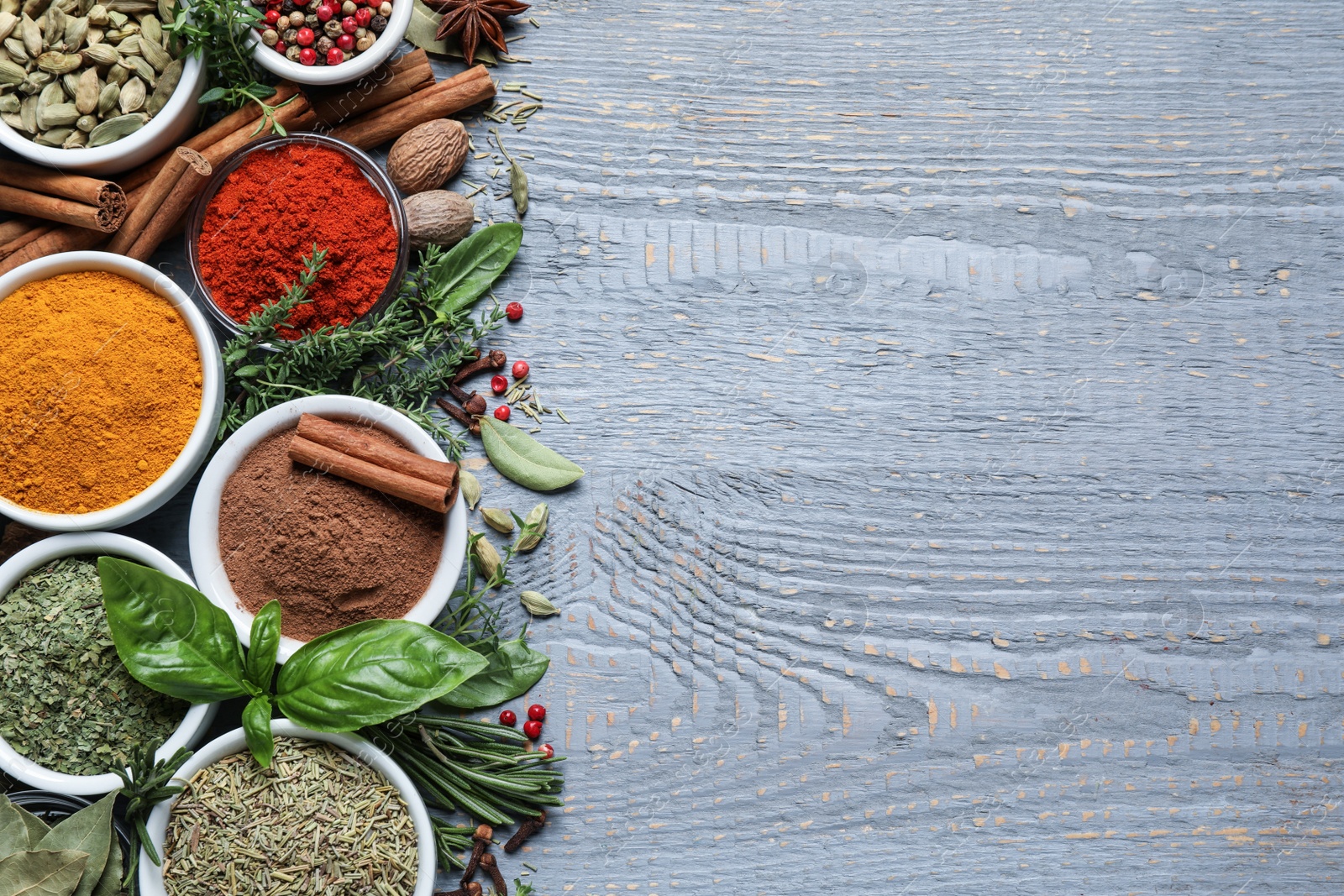 Photo of Different natural spices and herbs on grey wooden table, flat lay. Space for text