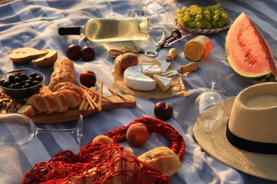Photo of Many different tasty snacks and wine on picnic blanket