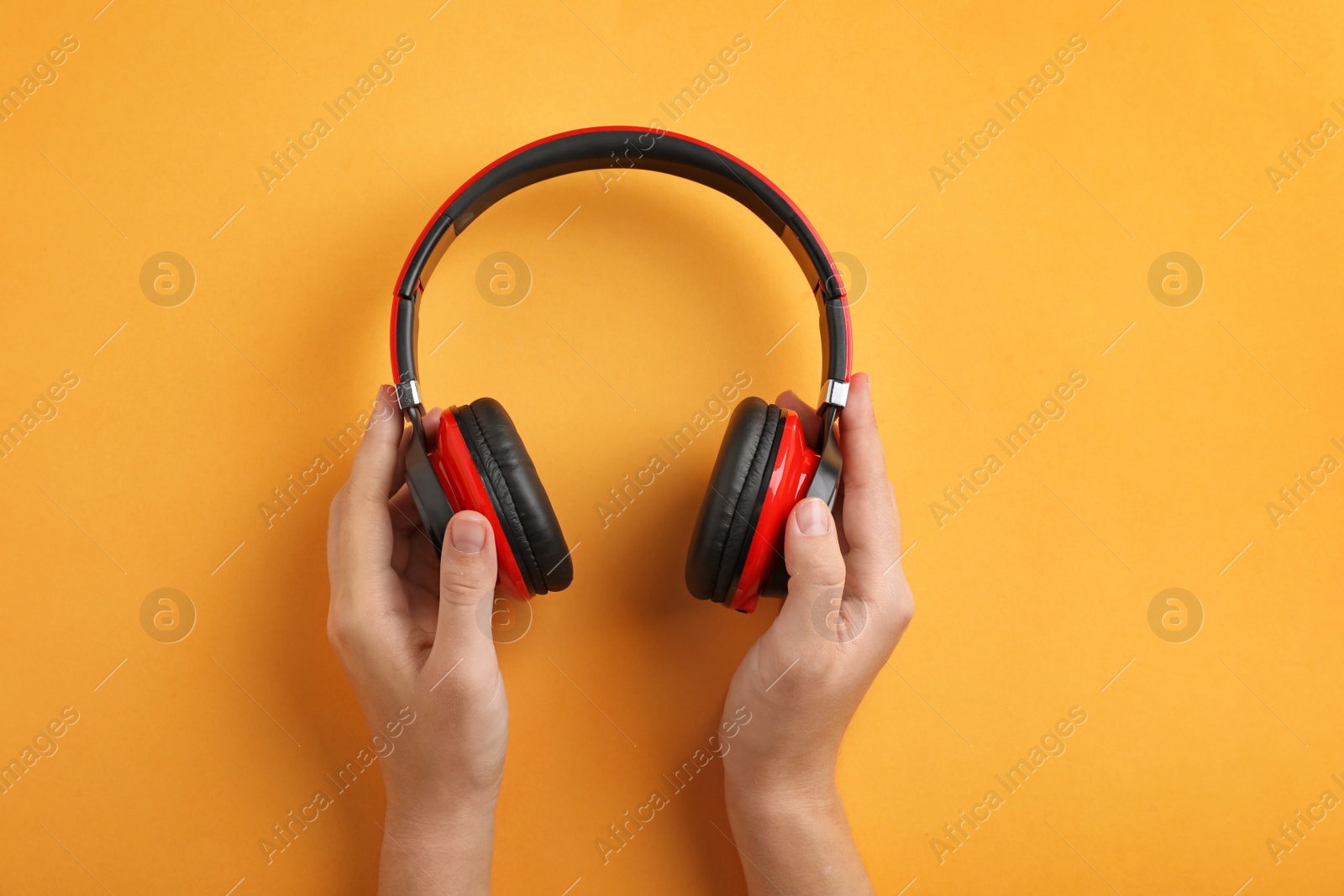 Photo of Woman holding headphones on color background, top view