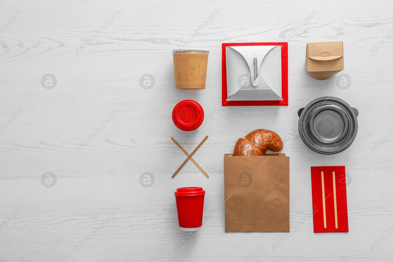 Photo of Flat lay composition with paper bag and different takeaway items on wooden background. Space for design