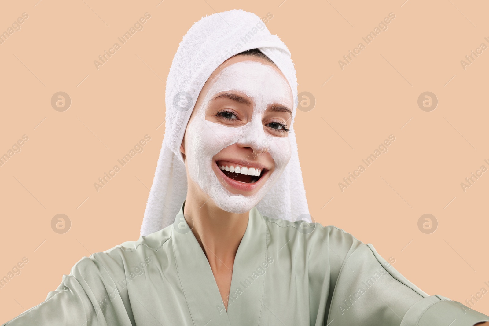 Photo of Woman with face mask taking selfie on beige background. Spa treatments