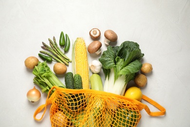 Fresh vegetables in eco mesh bag on white background, flat lay