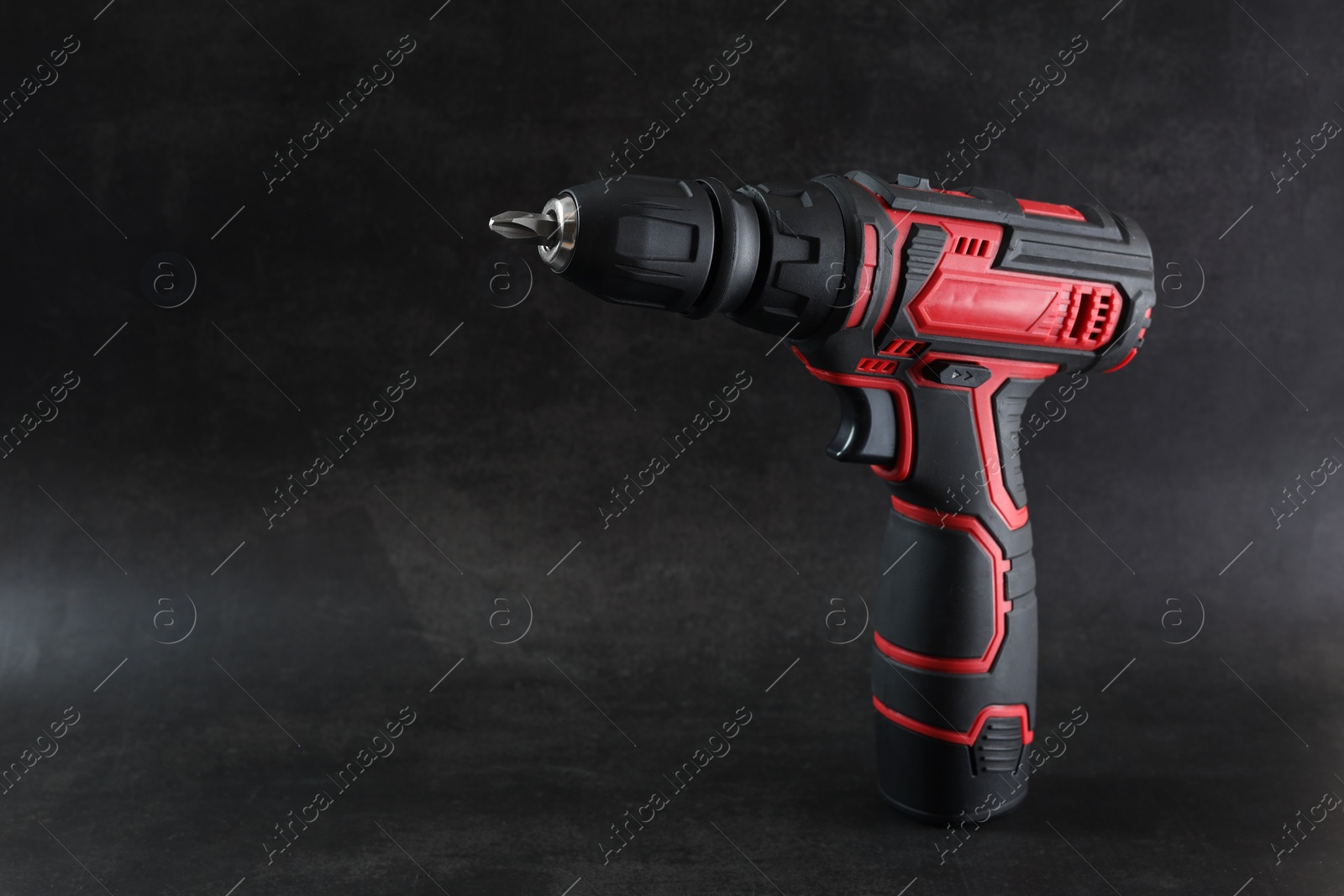 Photo of Modern electric screwdriver on dark grey background. Space for text