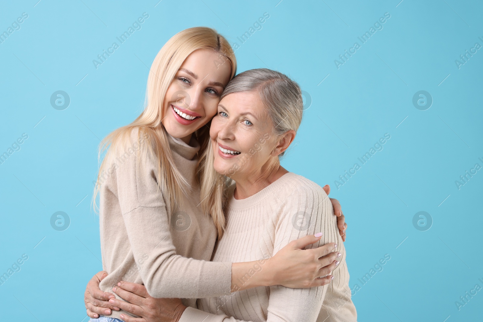 Photo of Family portrait of young woman and her mother on light blue background