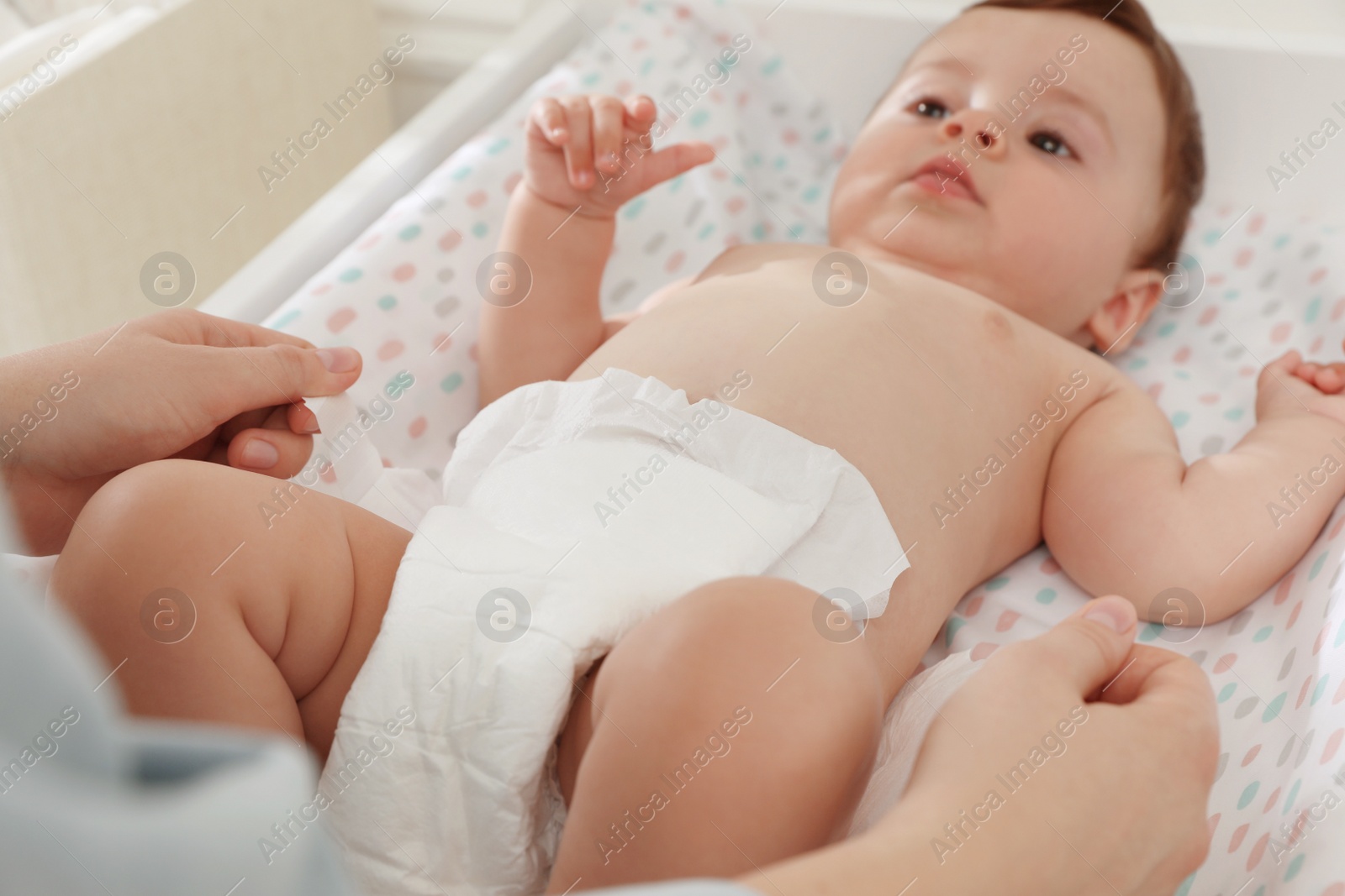 Photo of Mother changing baby's diaper on table at home, closeup