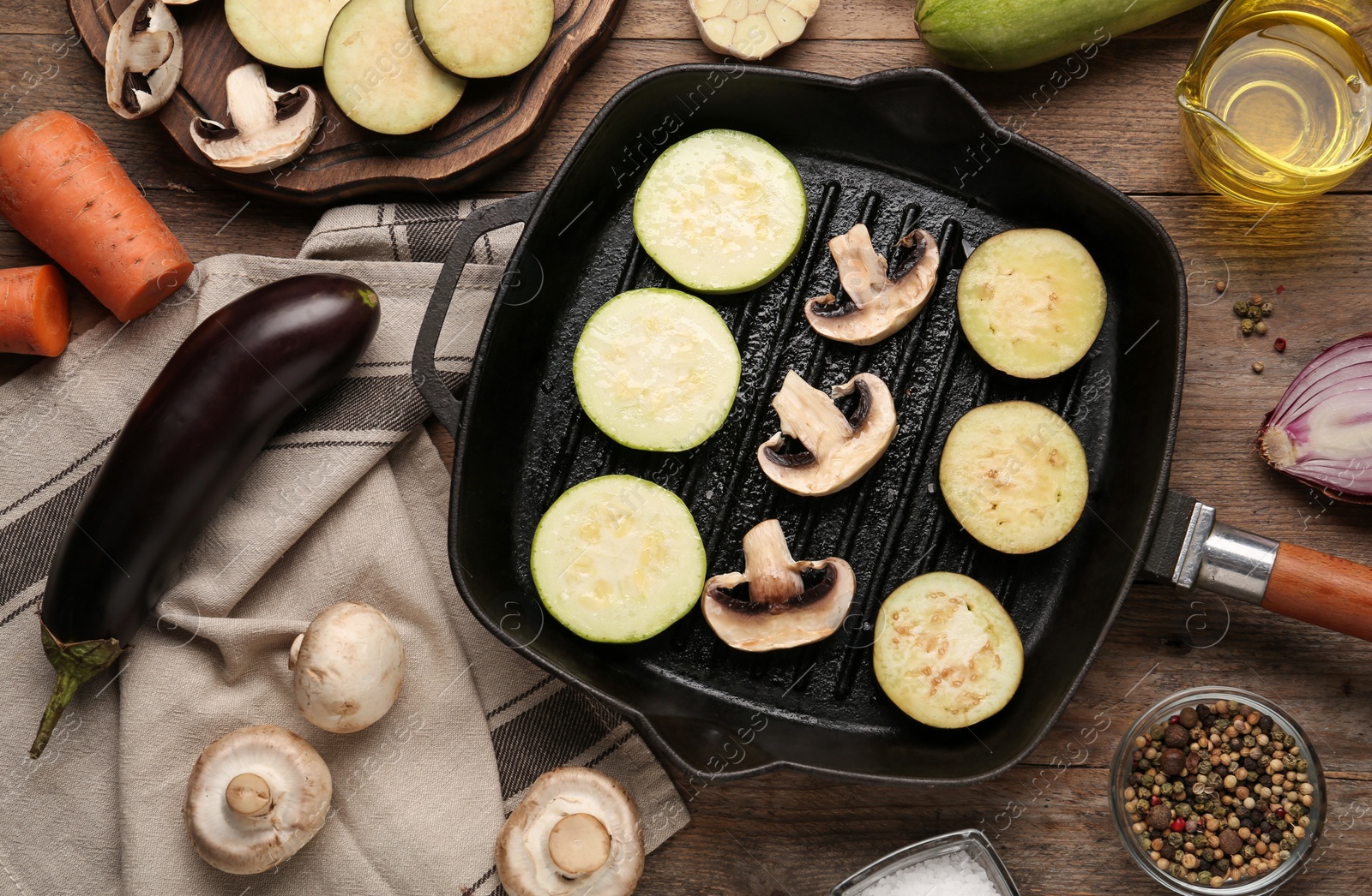 Photo of Grill pan and fresh vegetables on wooden table, flat lay