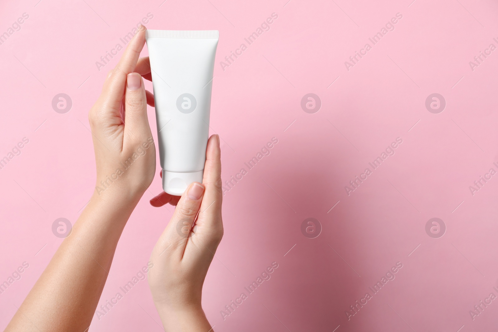 Photo of Woman with tube of hand cream on pink background, closeup. Space for text