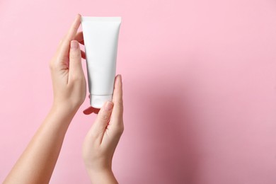 Photo of Woman with tube of hand cream on pink background, closeup. Space for text