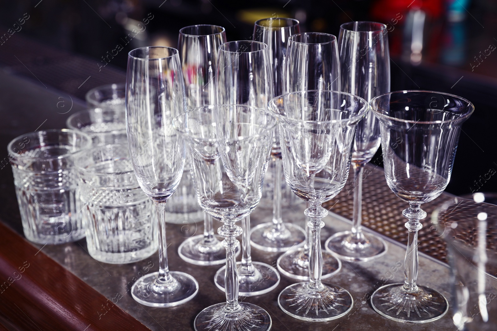 Photo of Different empty clean glasses on counter in bar