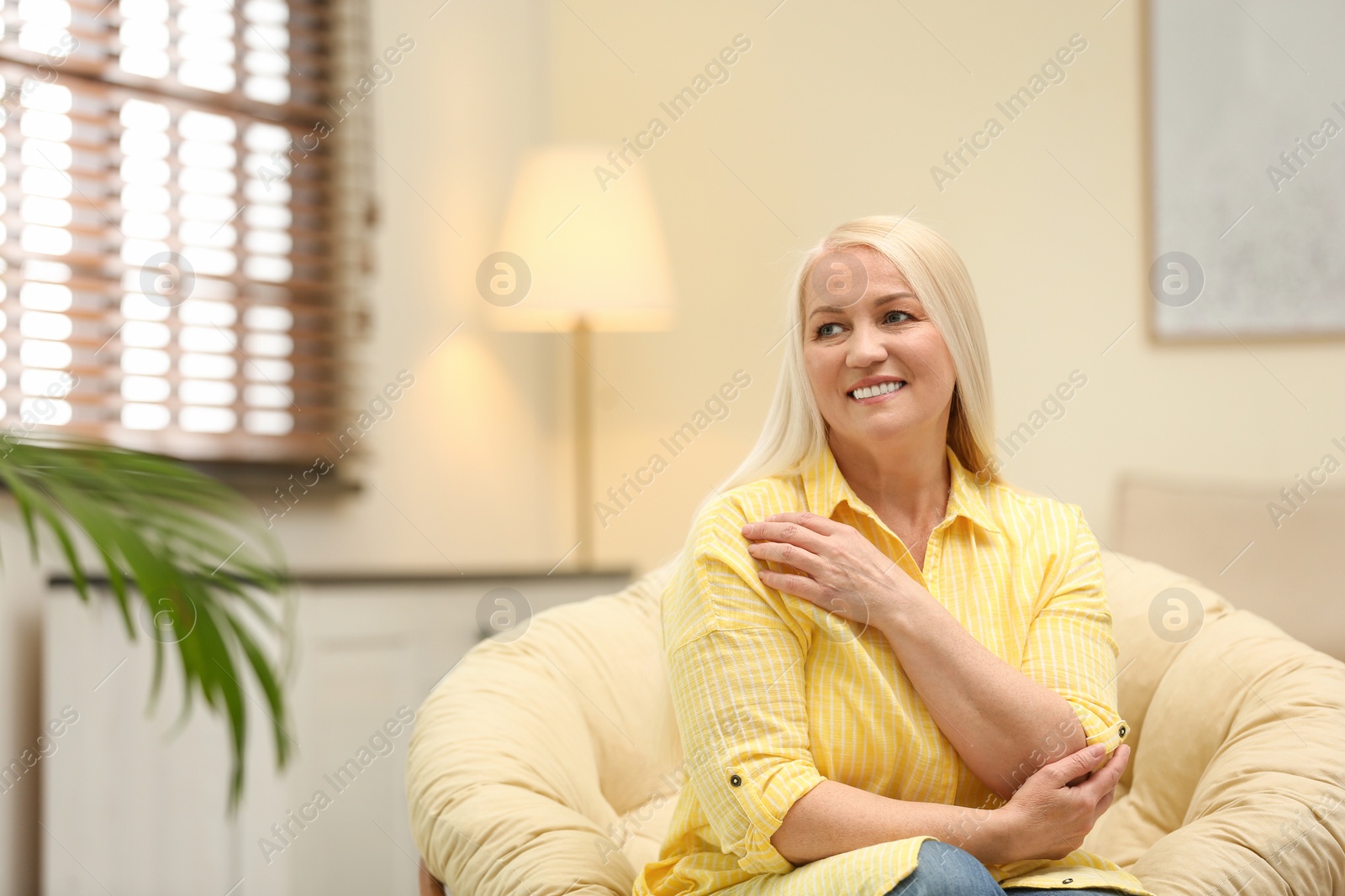 Photo of Portrait of happy mature woman sitting in papasan chair at home