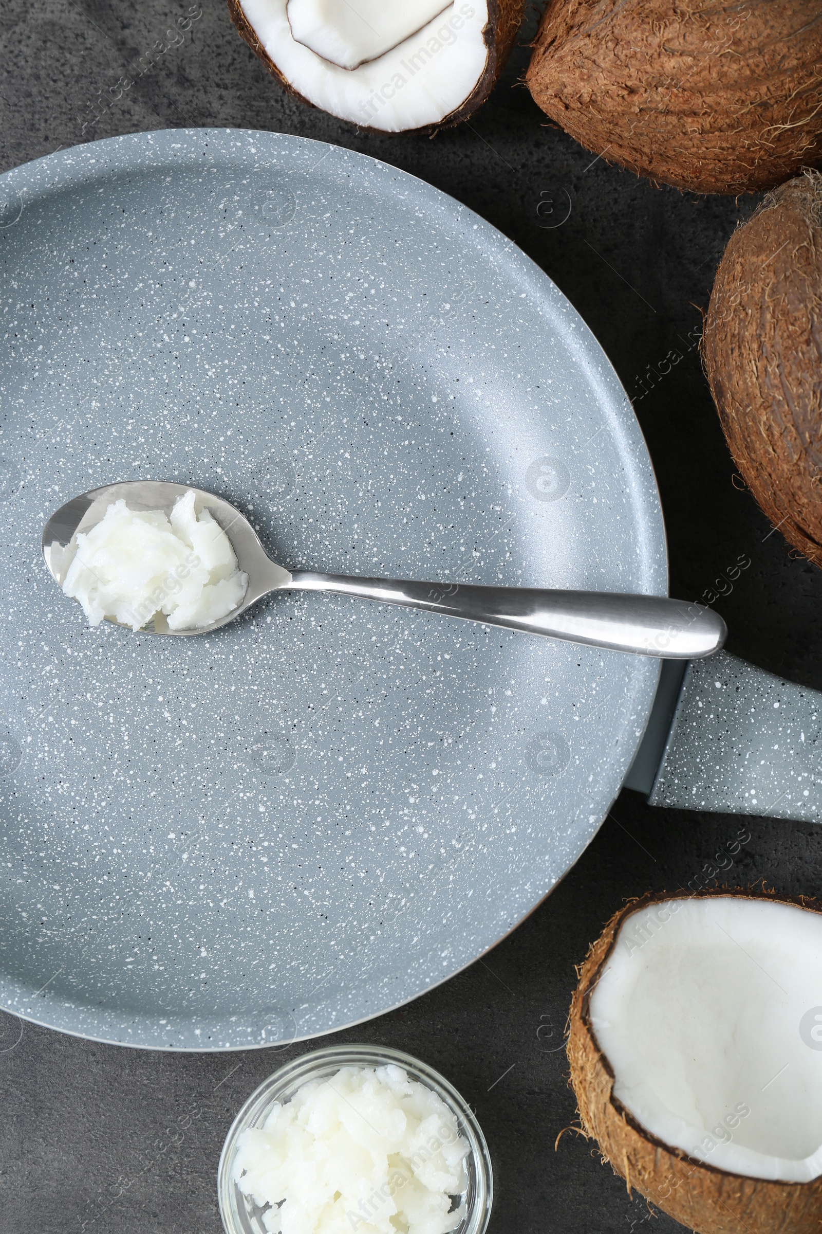 Photo of Flat lay composition with frying pan and organic coconut cooking oil on grey table