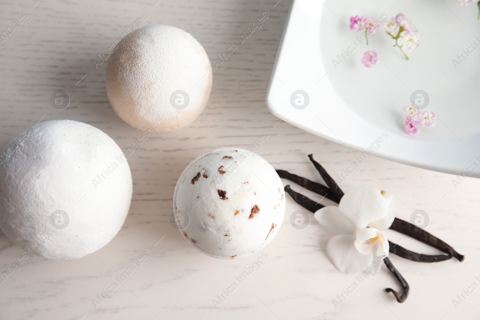 Photo of Flat lay composition with bath bombs and vanilla pods on white wooden background