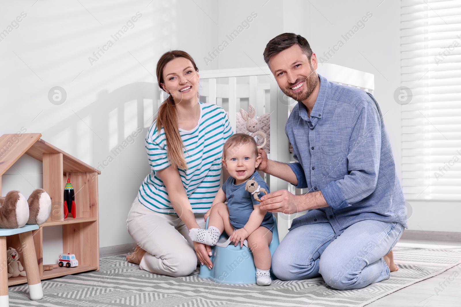 Photo of Parents training their child to sit on baby potty indoors