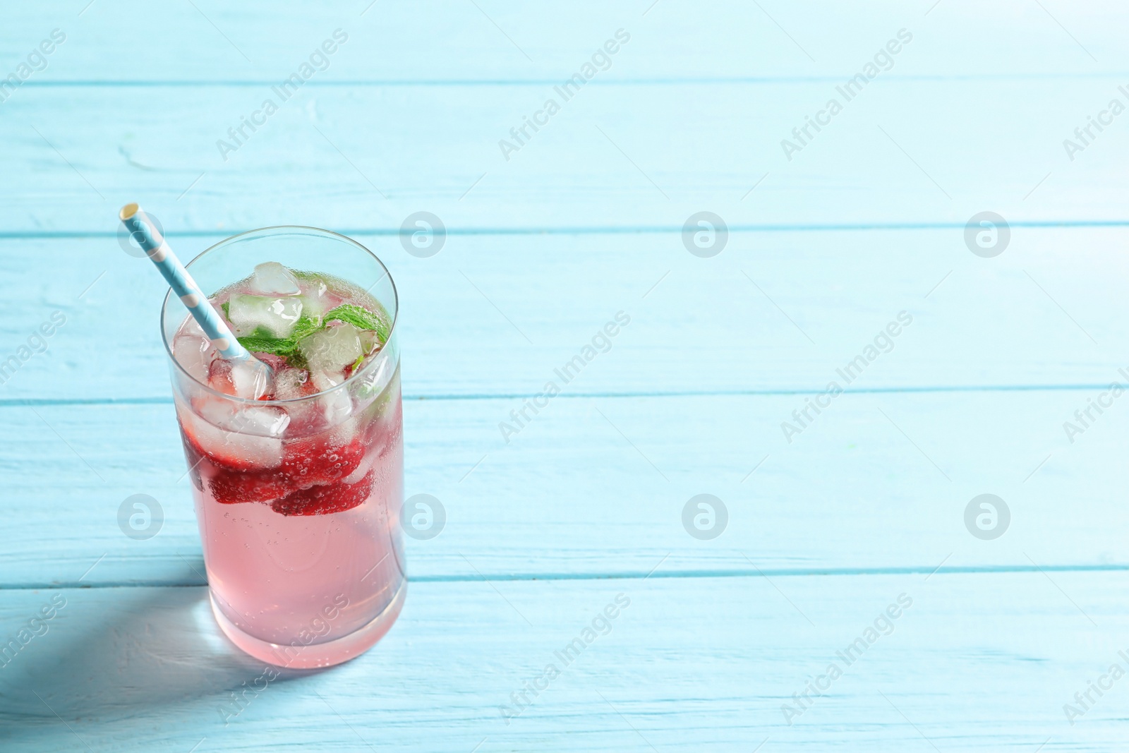 Photo of Natural lemonade with strawberries in glass on wooden table