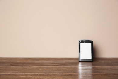 Photo of Napkin holder with paper serviettes on table against color background. Space for text