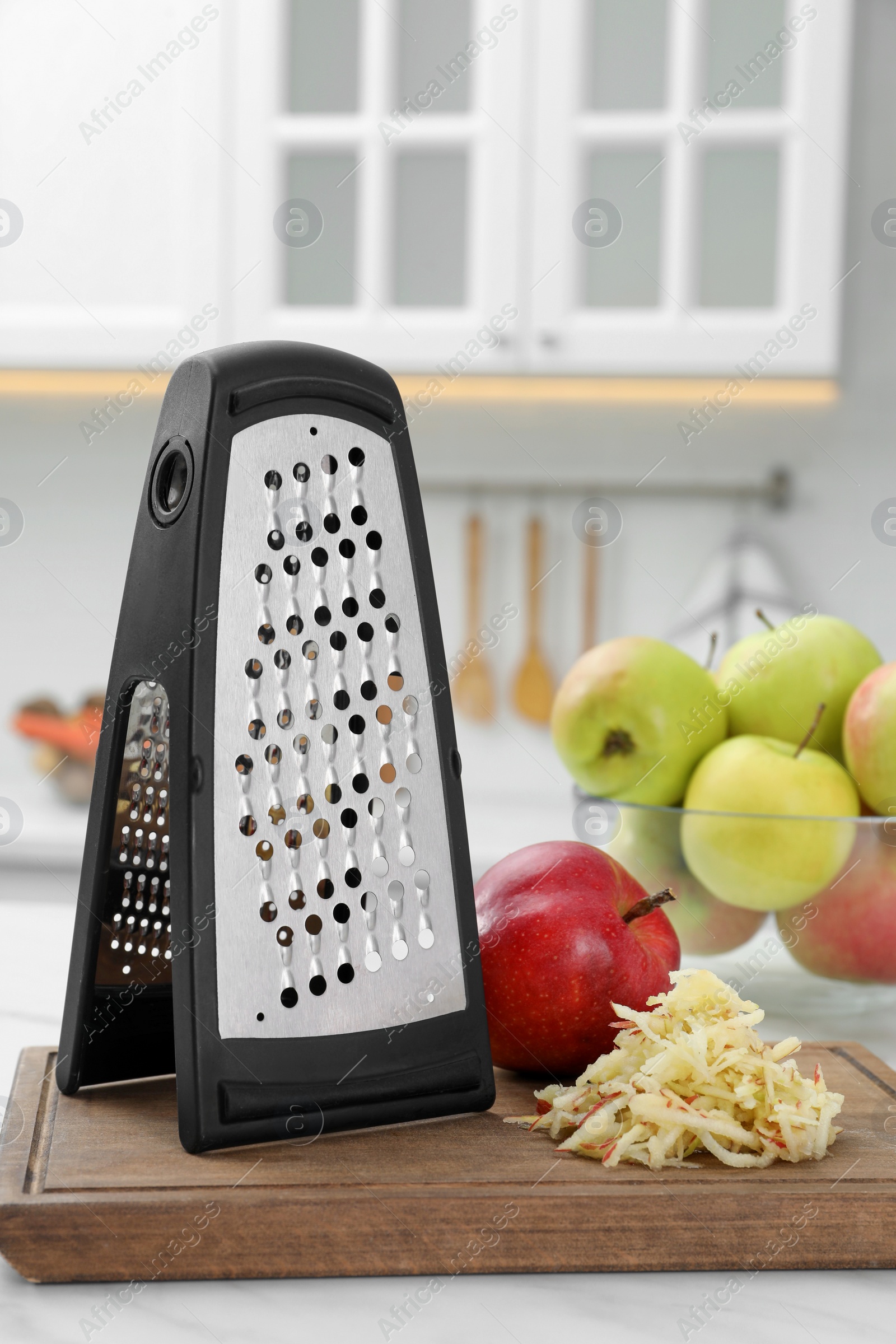 Photo of Grater and fresh ripe apples on white table in kitchen